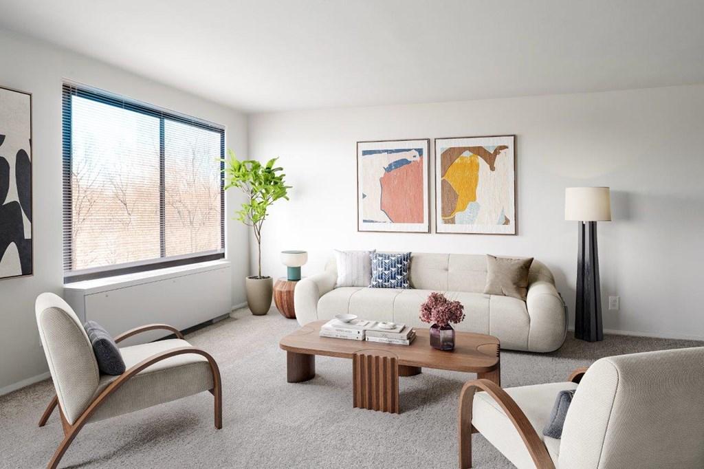A living room with a white couch, a wooden coffee table, and a large window.