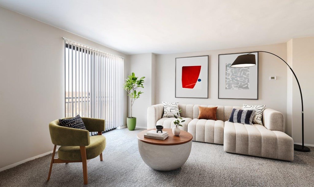 A living room with a green chair, a white sofa, and a red abstract painting on the wall.