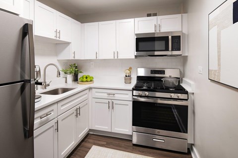 A modern kitchen with white cabinets and stainless steel appliances.