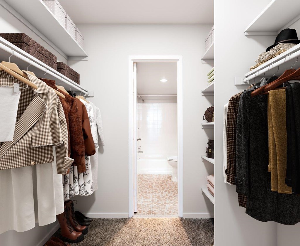 A hallway with a white door and clothes hanging on both sides.