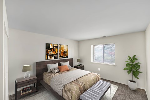 A bedroom with a bed, nightstand, and a plant.