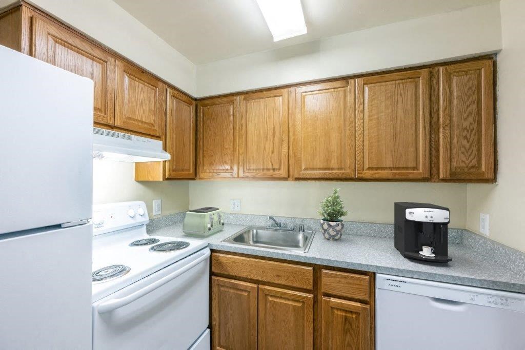 a kitchen with white appliances and wooden cabinets