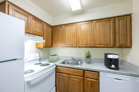 an empty kitchen with white appliances and wooden cabinets