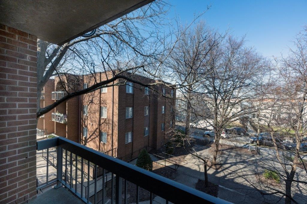 a balcony with a view of a brick building and some trees