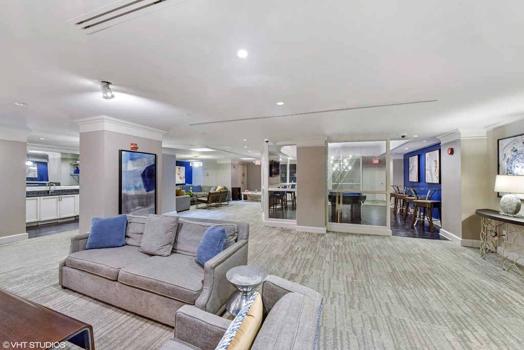 A spacious clubroom with a grey couch and a coffee table.