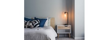 a bedroom with a bed with pillows and a nightstand with a lamp