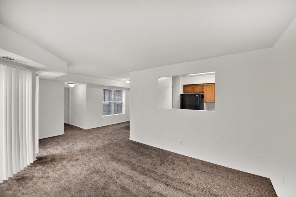 a living room with carpet and a black refrigerator