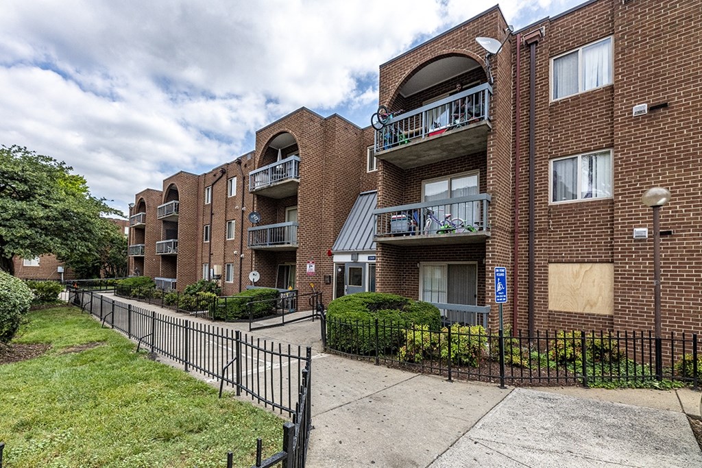 an apartment building with a sidewalk and a fence