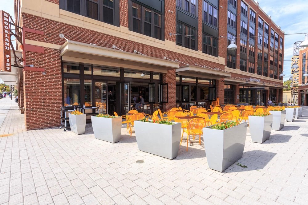 the outside of a Brookland Pint with yellow chairs and tables at Brookland Ridge Apartments, Washington, 20017