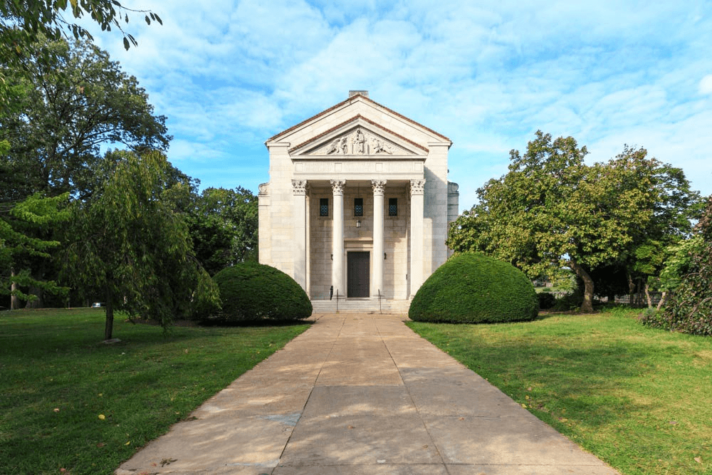 a large white building with a walkway and trees