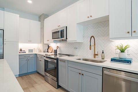 A modern kitchen with white cabinets and a marble backsplash.