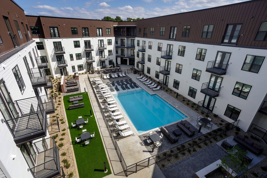 A large outdoor pool surrounded by lounge chairs and umbrellas.