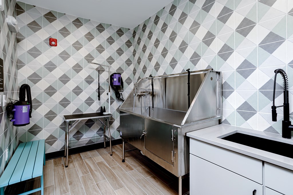 A kitchen with a white tile wall and a stainless steel sink.