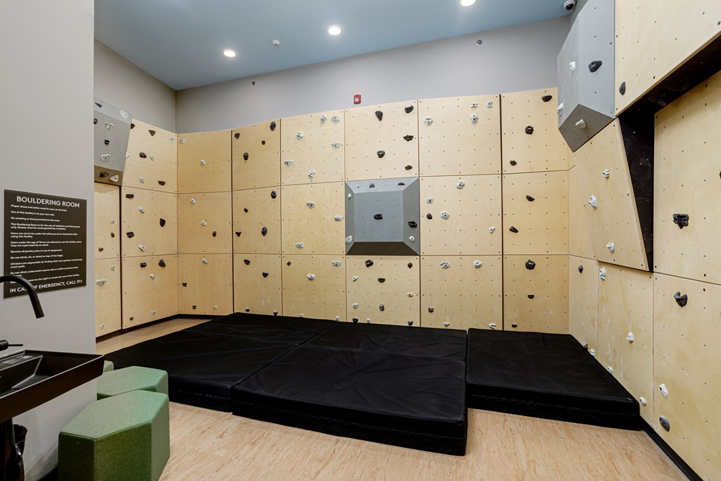 A bouldering room with a wooden floor and a wall covered in climbing holds.
