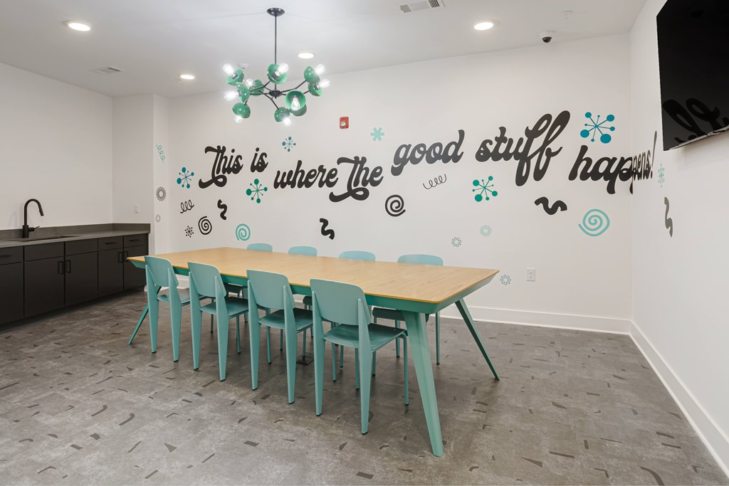 A conference room with a long table and chairs and a quote on the wall.