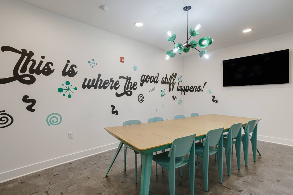 A room with a long table and chairs and a quote on the wall.