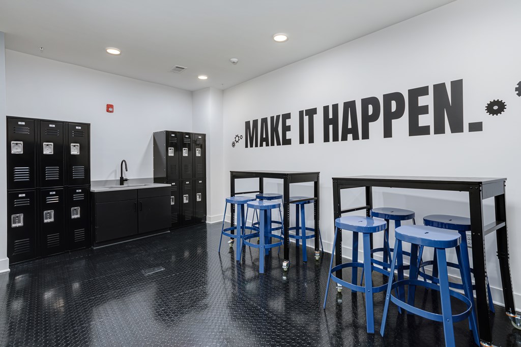 A black and white room with blue stools and a wall that says "Make it happen".