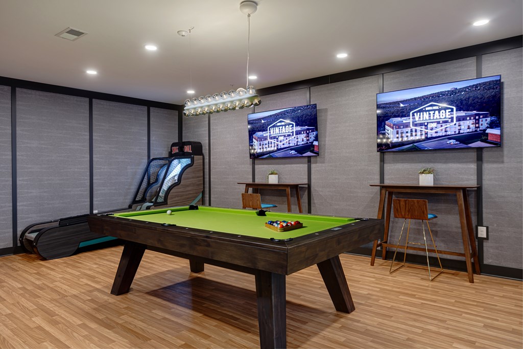 A room with a pool table and a TV screen showing the word "VINTAGE".