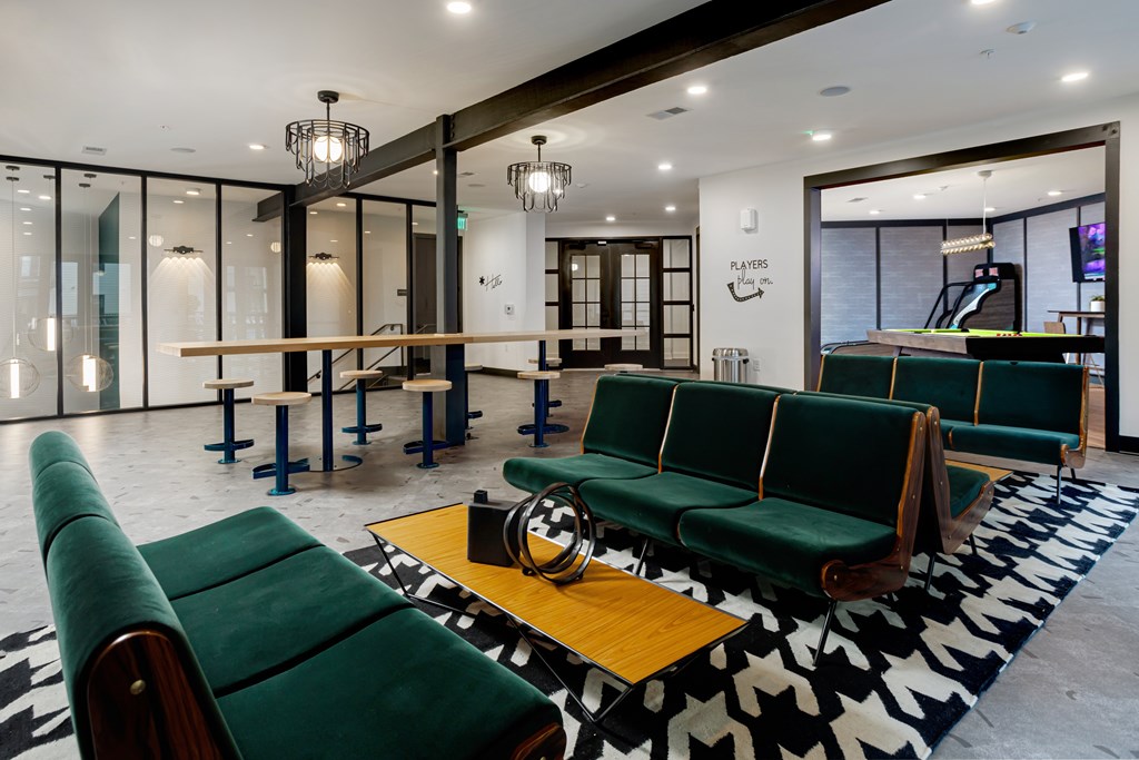 A room with green couches and a black and white rug.