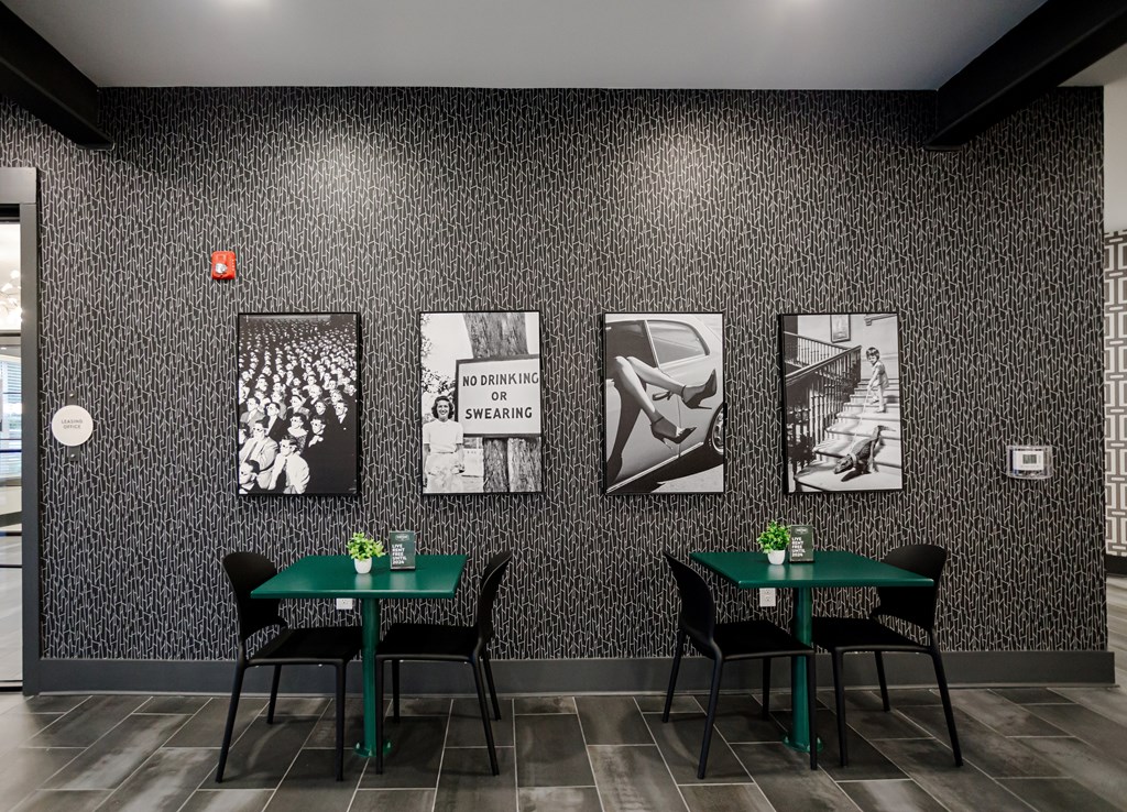 A black and white photo is on the wall above a table with a green tablecloth and two chairs.