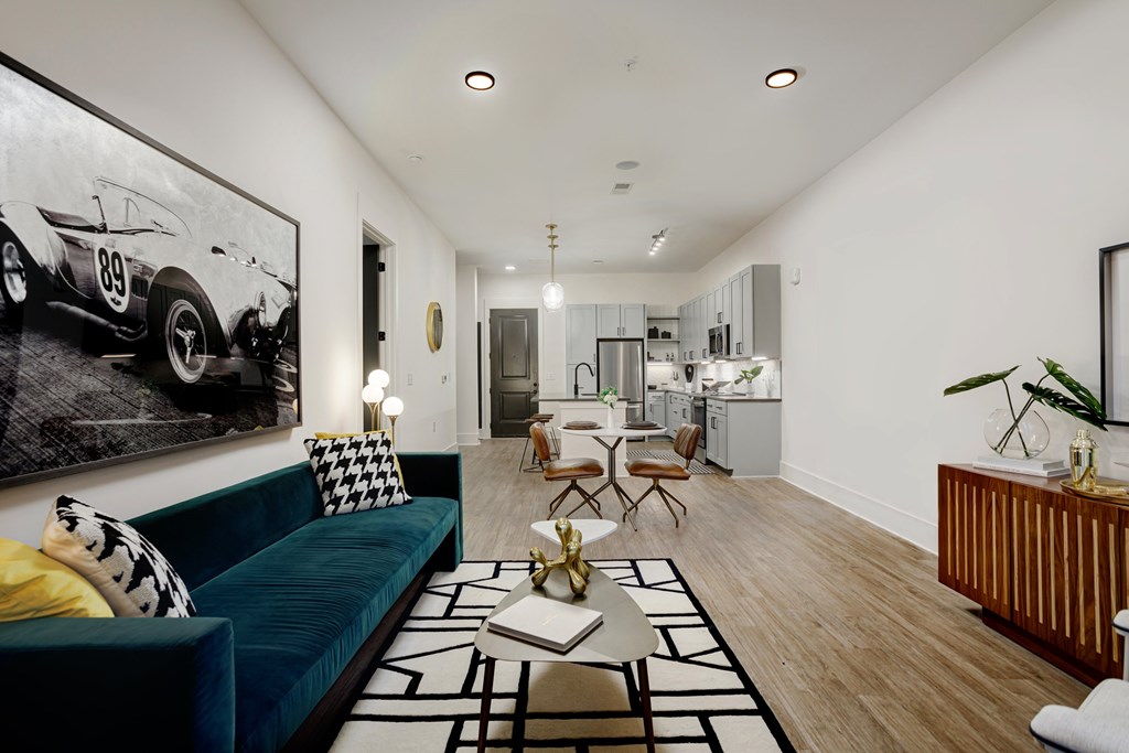 A living room with a blue couch and a black and white photo of a race car on the wall at Vintage Edge Nashville Apartments, Nashville, TN
