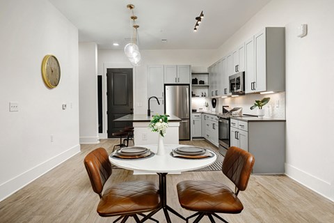 A modern kitchen with a dining table set for two.