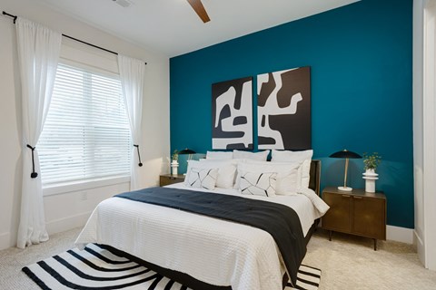 A bedroom with a bed, nightstand, and a large abstract painting on the wall at Vintage Edge Nashville Apartments, Nashville, TN
