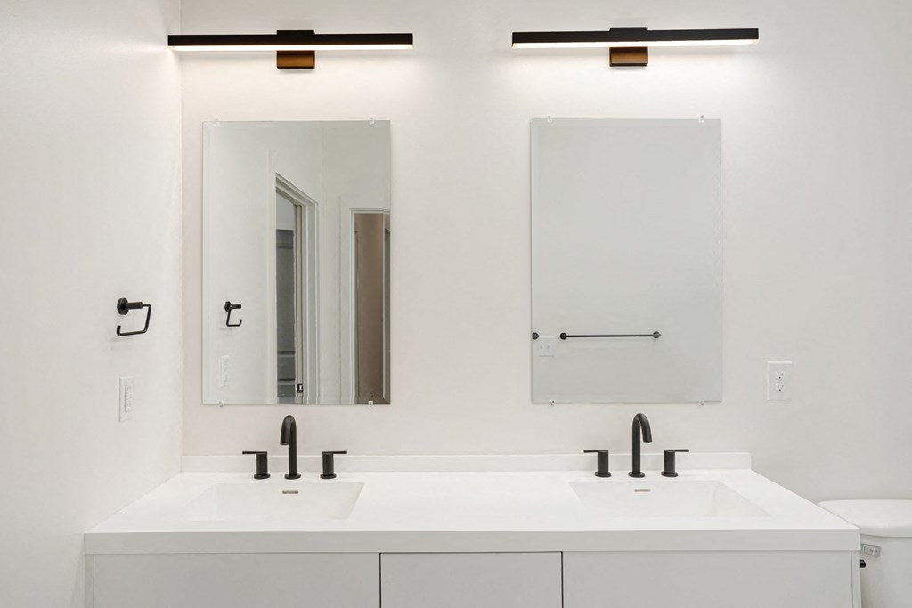A white bathroom with two sinks and a mirror above each at Vintage Edge Nashville Apartments, Nashville