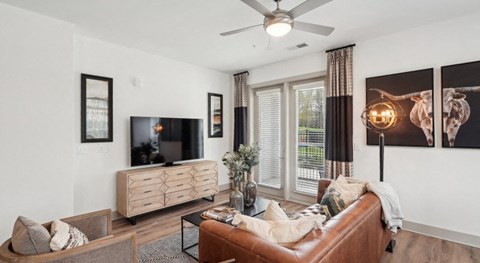 A living room with a brown leather couch and a flat screen TV.