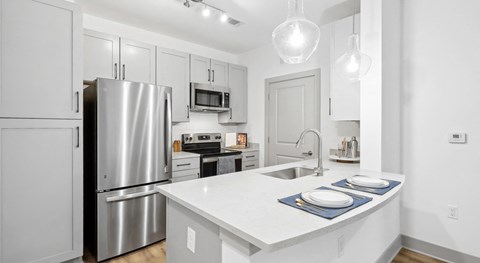 A modern kitchen with a stainless steel refrigerator and white countertops.