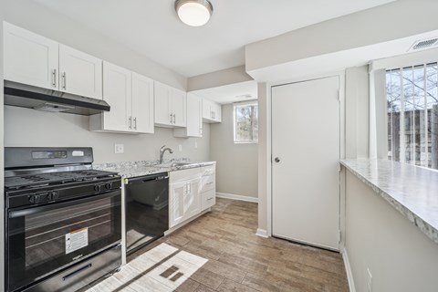 A kitchen with a black stove top oven and white cabinets.