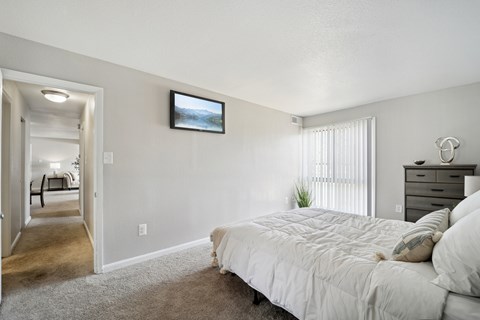 A bedroom with a large bed and a television mounted on the wall.