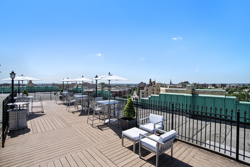 a rooftop terrace with tables and chairs and a view of the city