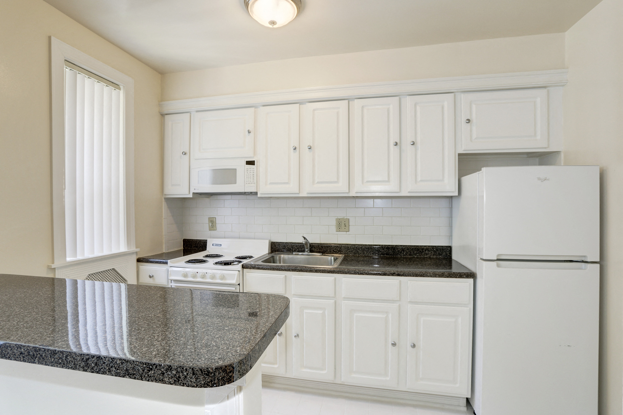 a kitchen with white appliances and granite counter tops