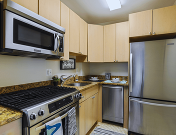 A kitchen with a stove, microwave, refrigerator, and cabinets.