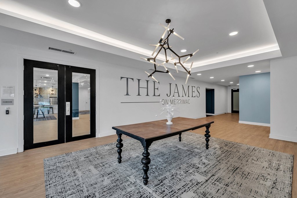 A room with a table and a chandelier with the name "The James" on the wall.