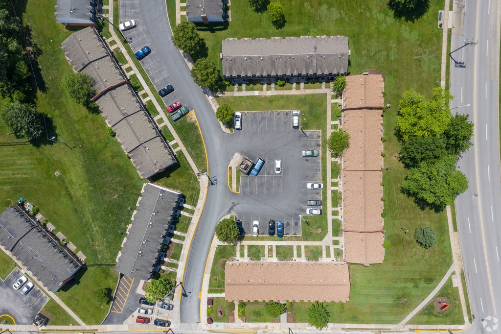 A parking lot is surrounded by a grassy area and a road.