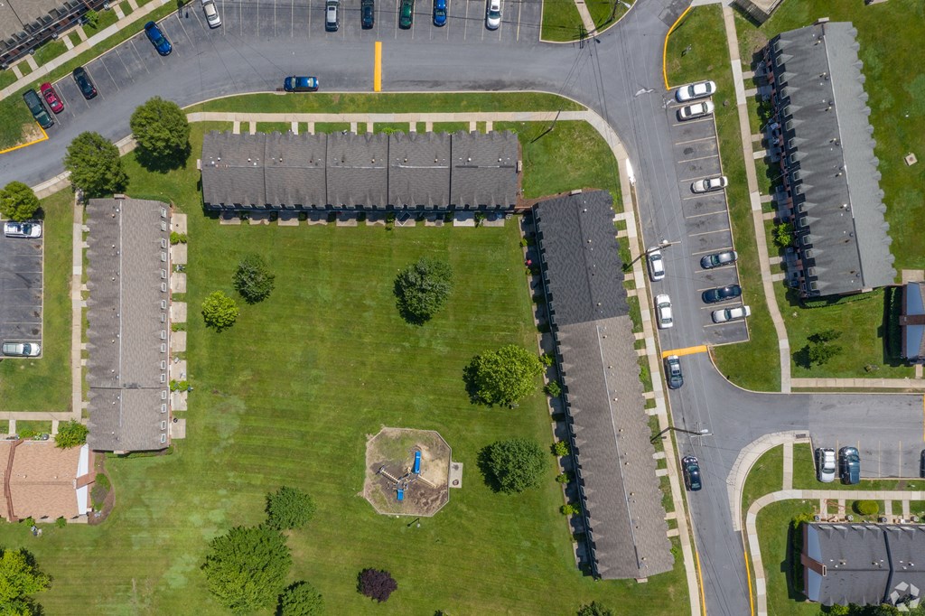 A bird's eye view of a residential area with houses, a playground, and a parking lot.