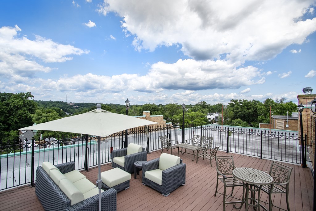 a rooftop deck with couches and tables and a pool