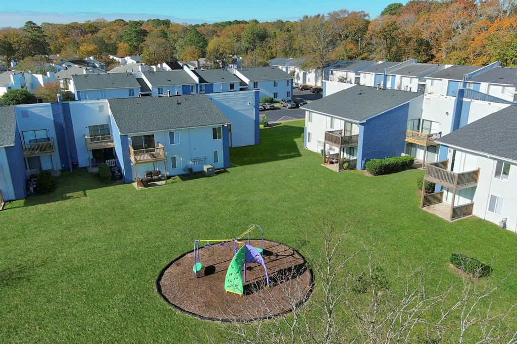 an aerial view of a group of blue houses and a yard with a playground