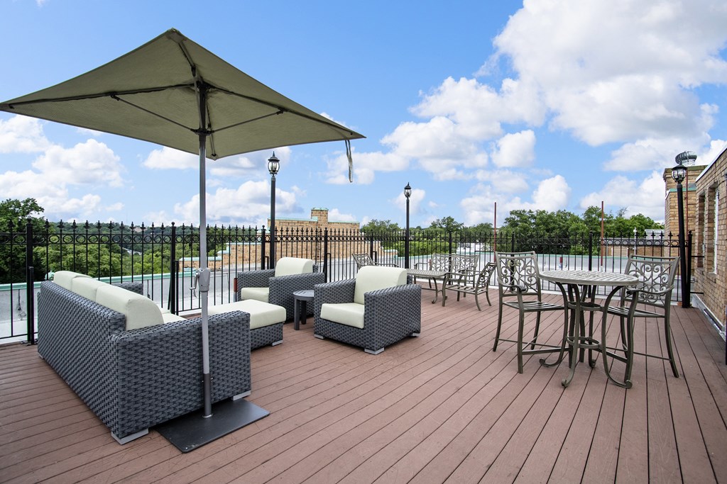 a rooftop patio with chairs and tables and an umbrella