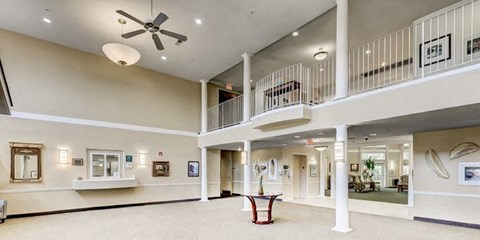 a large lobby with a ceiling fan and a balcony at Windsor Crossing Senior, Suitland, MD 20746 