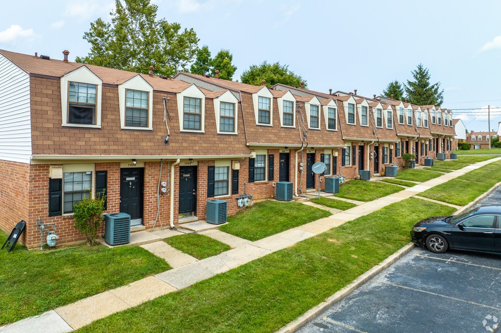 A row of red brick houses with green lawns in front.