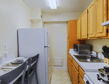 A kitchen with a white refrigerator, wooden cabinets, and a stove top oven.