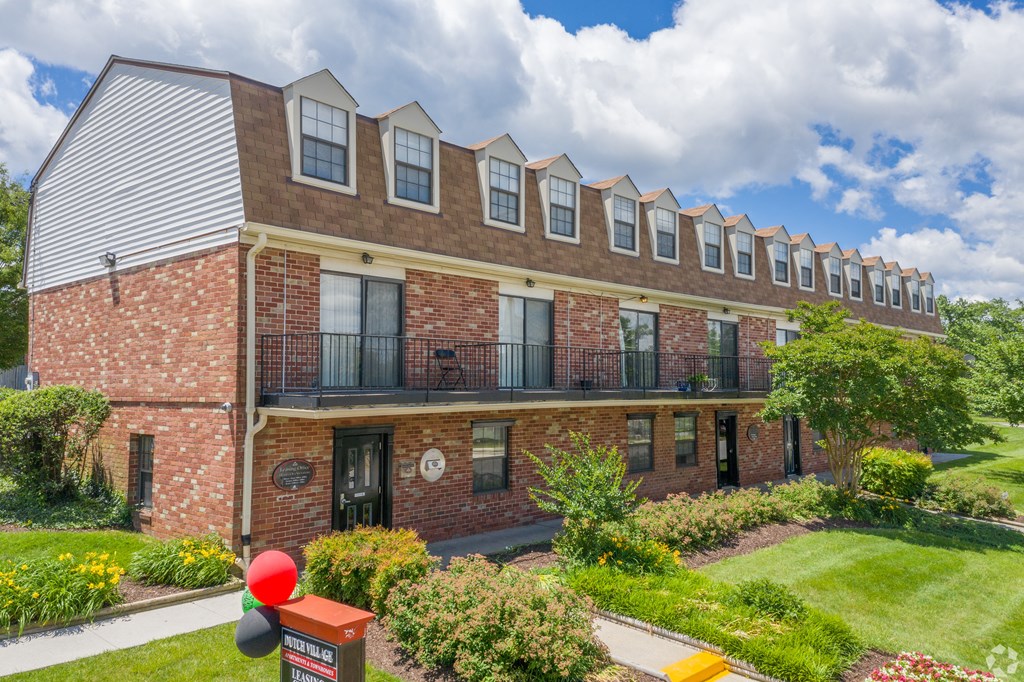 A red brick building with a balcony and a mailbox in front.