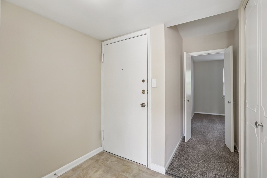 A white door with a handle and a lock is in a room with a carpet.
