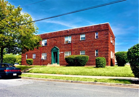 A red brick building with a green door and windows.
