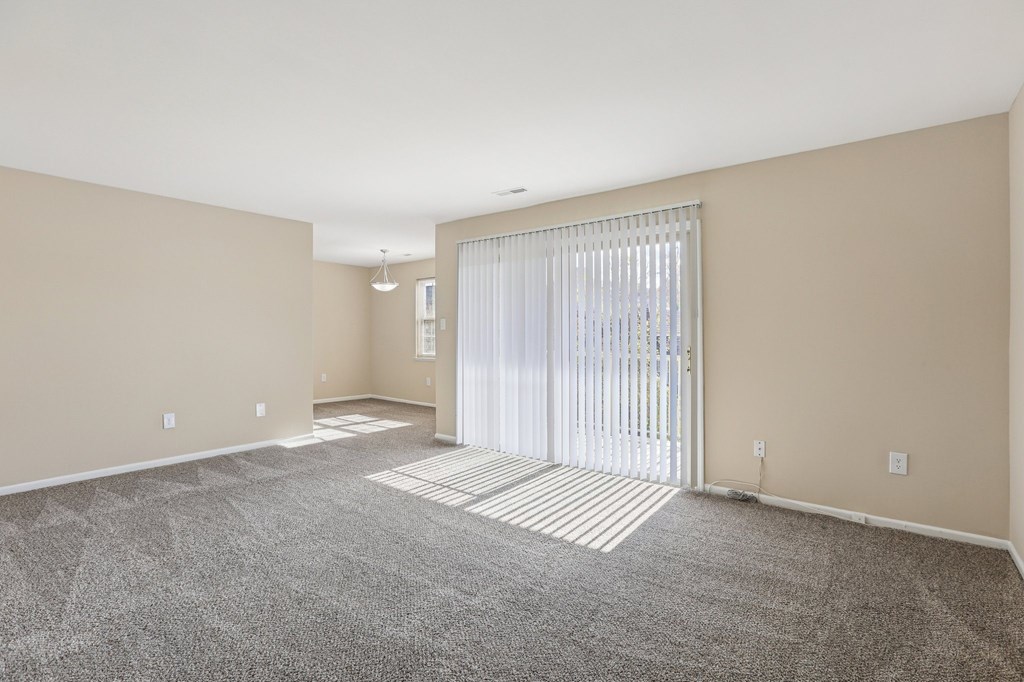 A spacious room with a carpeted floor and a sliding glass door.