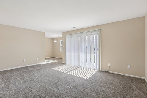 A spacious room with a carpeted floor and a sliding glass door.