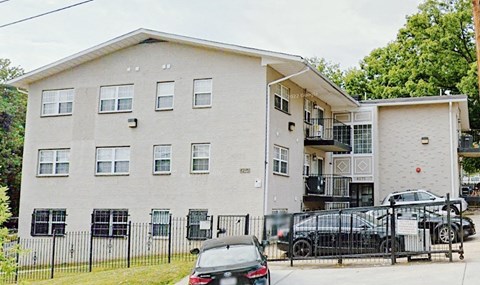 A white apartment building with a black fence in front.